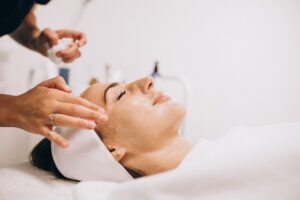 cosmetologa limpiando la cara de una mujer en un salon de belleza